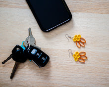 Load image into Gallery viewer, Handmade paper quilled light weight dangle earrings in deep yellow and pumpkin colors inspired by the Fall / Autumn season&#39;s colors in fish hook style. Set in a scene next to cellphone and keys, just grab your earrings as you step outside the door..
