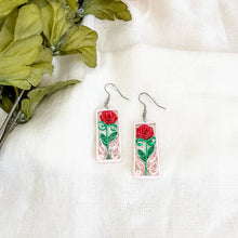 Load image into Gallery viewer, Handmade earrings with a paper quilled red rose and leaves, captured in a light pink frame.
